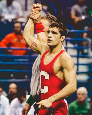 A Cornell University wrestler with his arm in the air after winning a match.