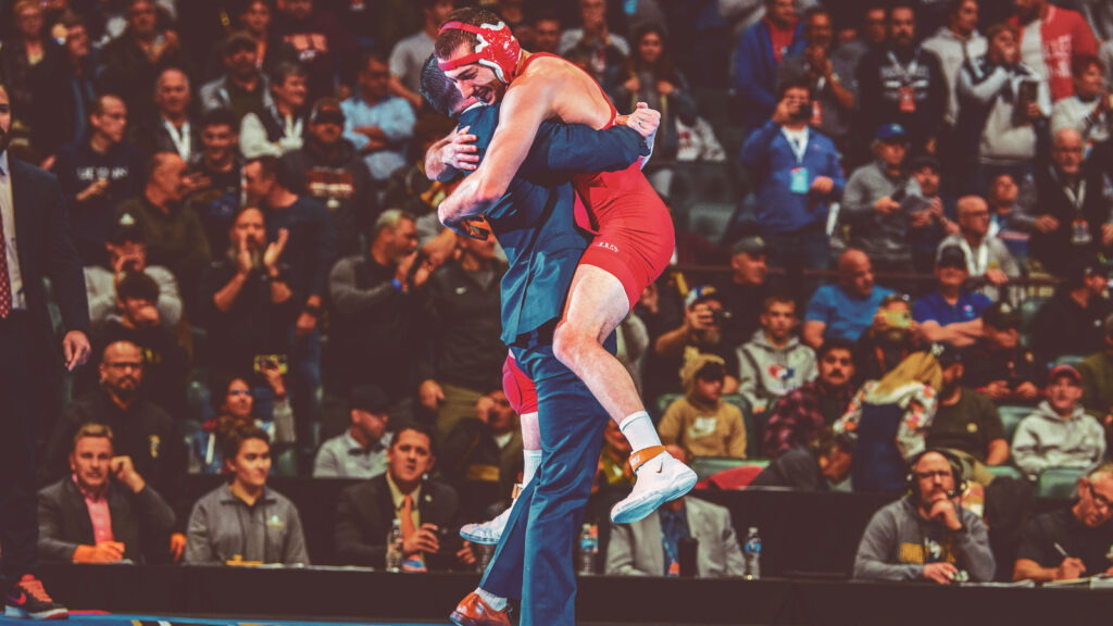 A wrestler hugs his coach at a wrestling tournament.
