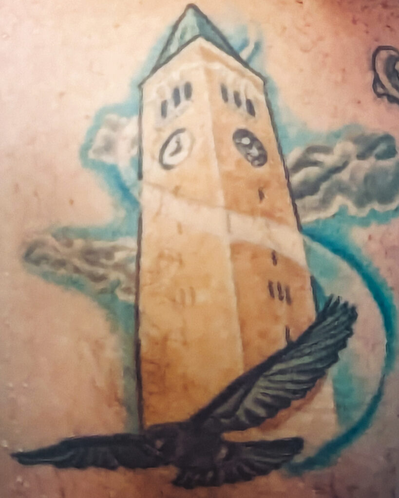 A tattoo of a raven flying around Cornell University's McGraw Tower.