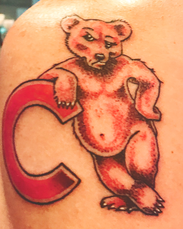 A red and black tattoo of Cornell University's logo on a man's shoulder.