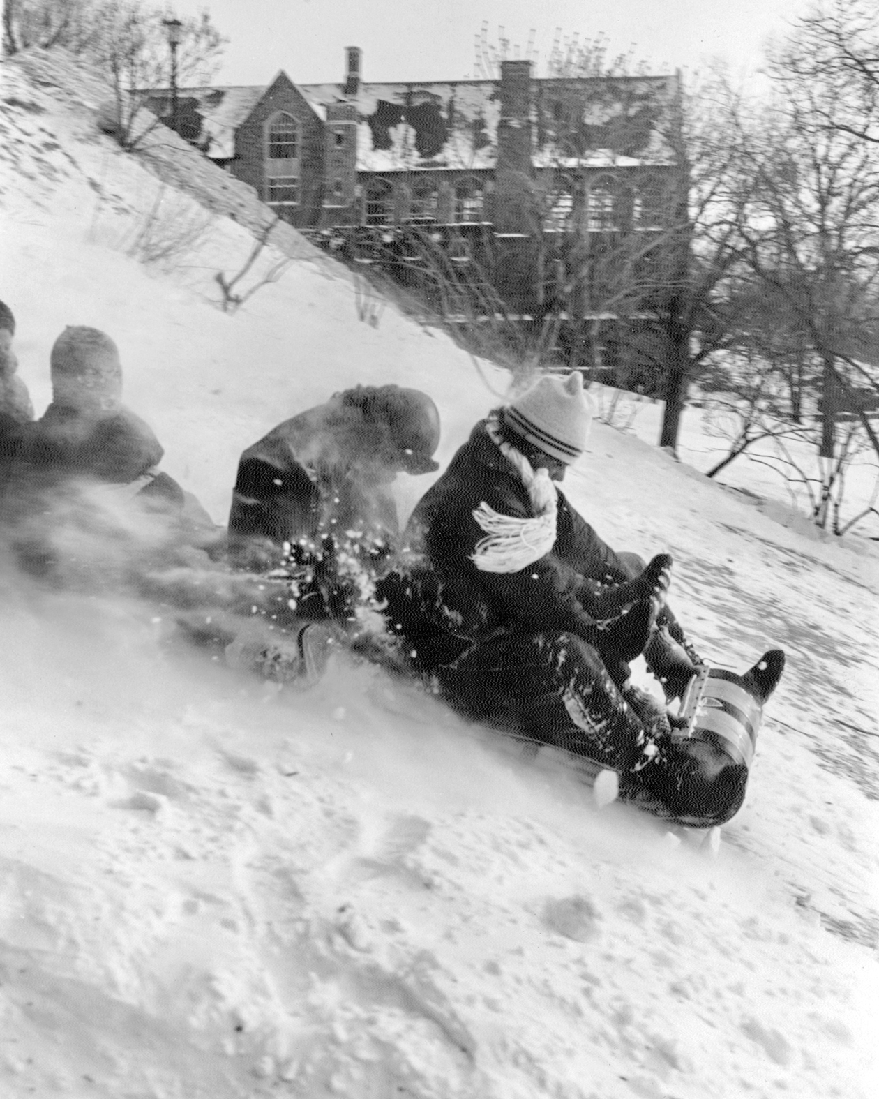 students ride a toboggan down a snowy Libe Slope
