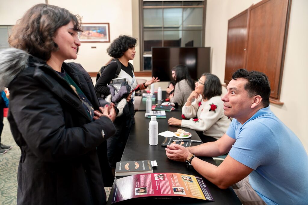 Manuel Muñoz chats with an attendee at a conference and book signing on campus in 2022
