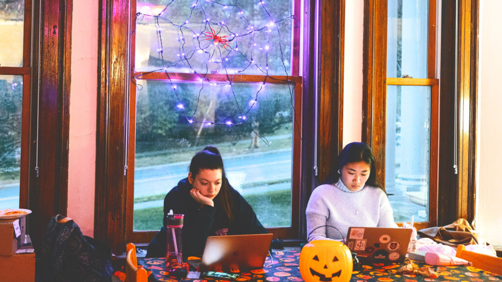 Amid Halloween decorations, two residents of the Veterans Program House study at a table