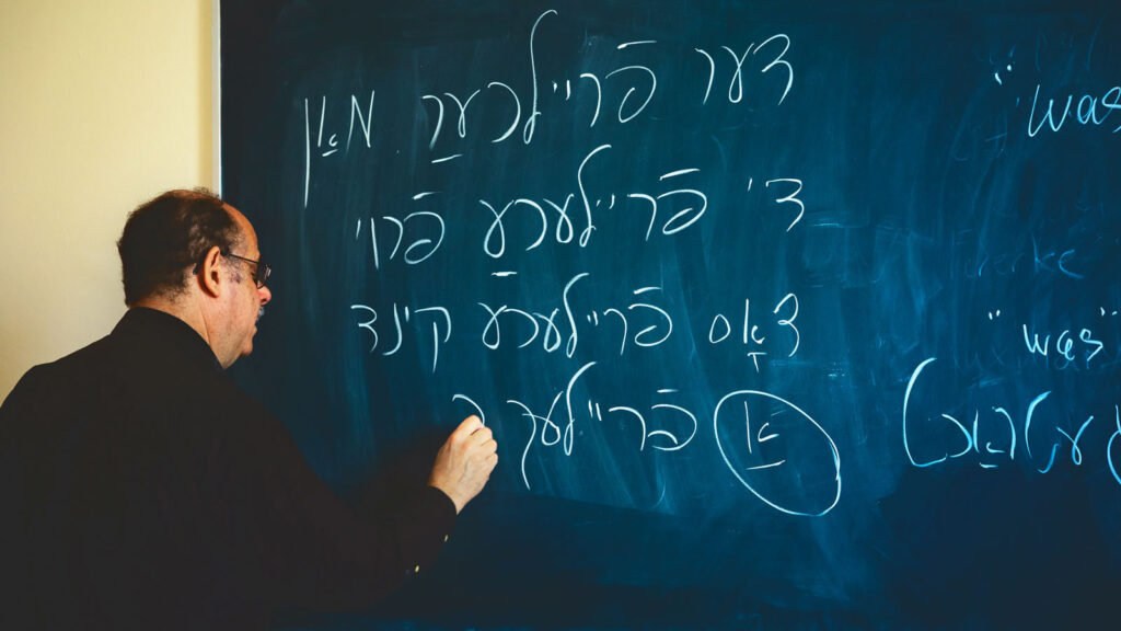 Yiddish instructor David Forman writes in Yiddish on a blackboard