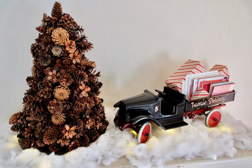 Faux snow and lights are placed under an antique toy and a pinecone tree for a classic look