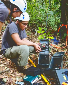 Two researchers preparing an audio recording unit in a forest.