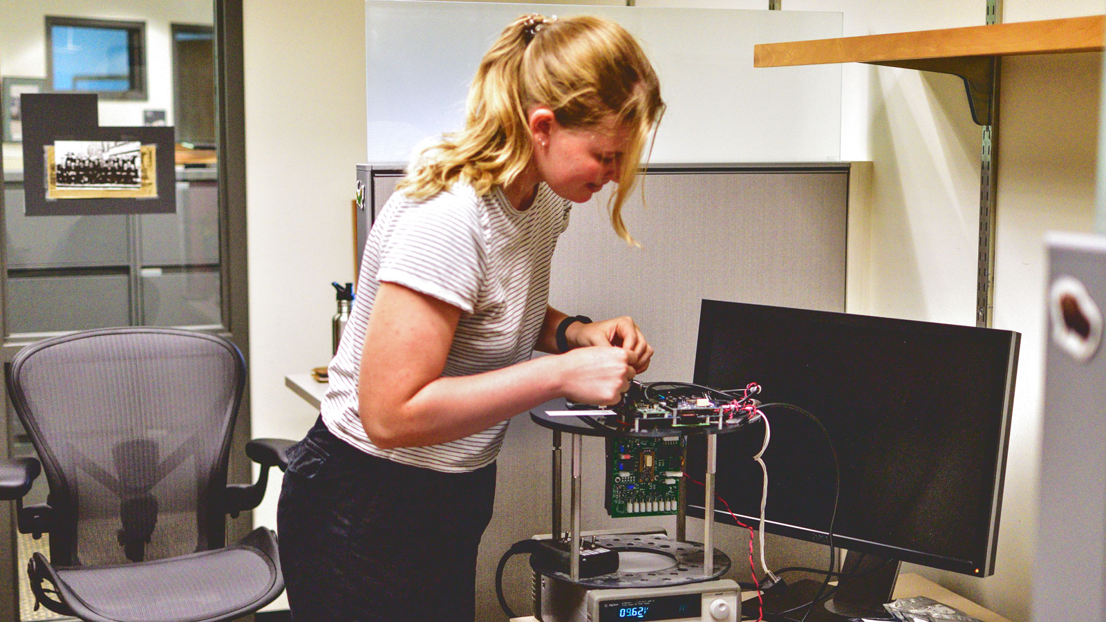 A woman in an office building audio recording hardware.