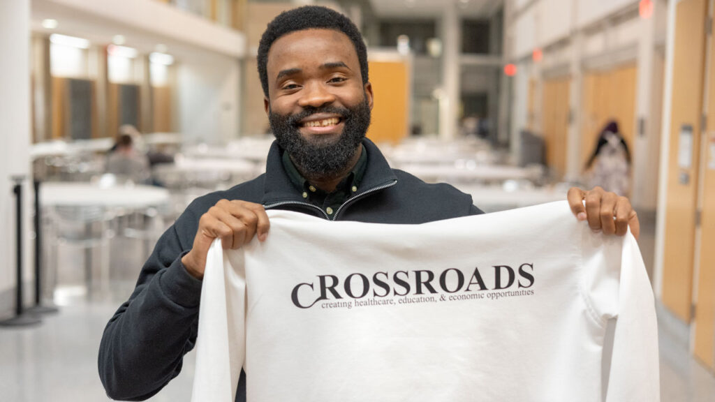 Kelechi Umoga '15, co-founder of Crossroads holds up a long sleeve shirt in the Physical Sciences Building