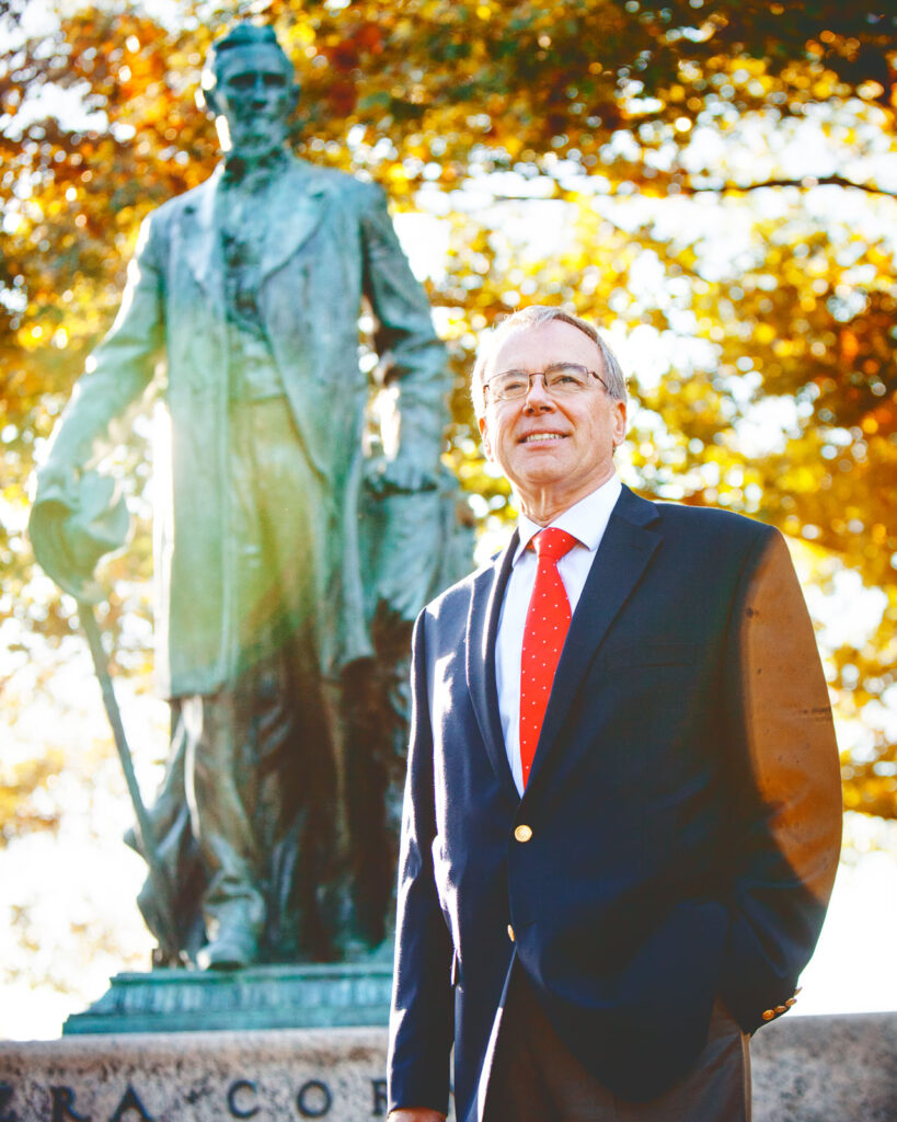 Ezra Cornell poses in front of the statue of the founder Ezra Cornell, his great-great-great grandfather