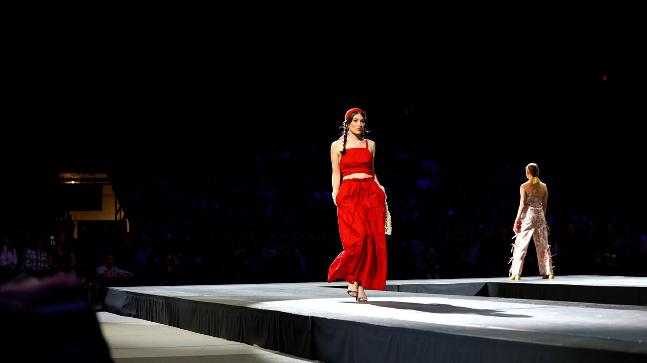 A model in bright red walks the runway during the 2024 40th Annual CFC Spring Fashion Show in Barton Hall, entitled Camera, Obscura.A model in bright red walks the runway during the 2024 40th Annual CFC Spring Fashion Show in Barton Hall, entitled Camera, Obscura.