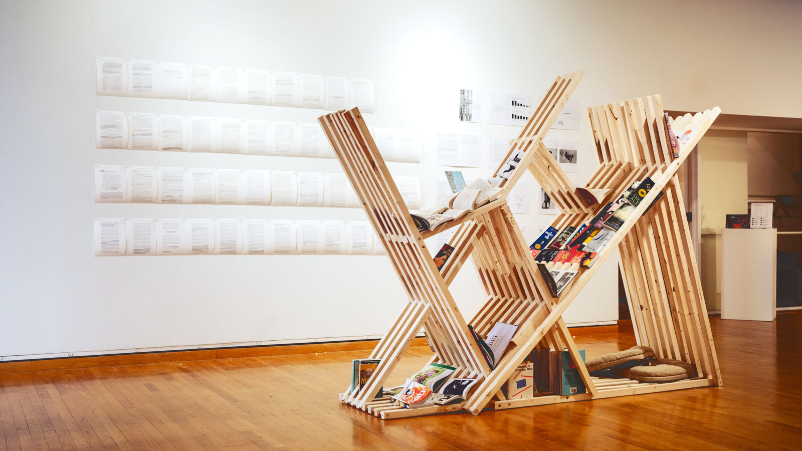 A wooden sculpture holding reading material, comprising the work "Bookmark for Freedom Pages"