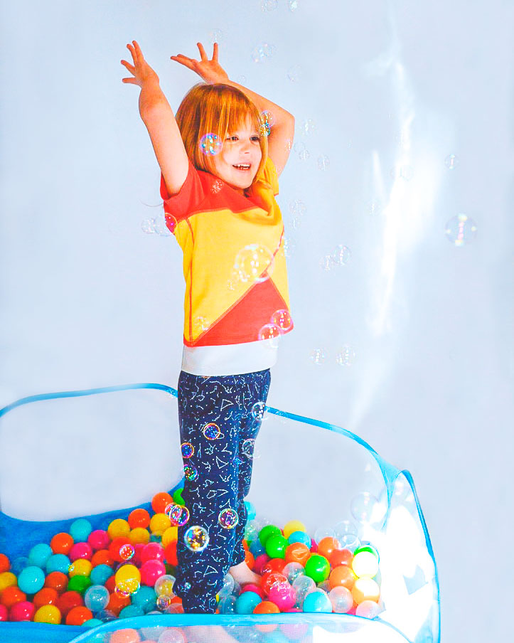 A child wears a compression shirt while playing in a ball pit with bubbles
