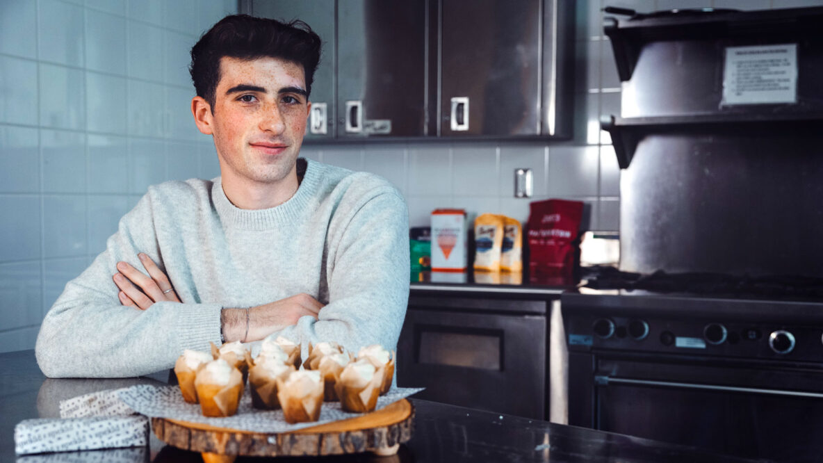 Jonah Gershon in a kitchen sitting behind a platter of cupcakes