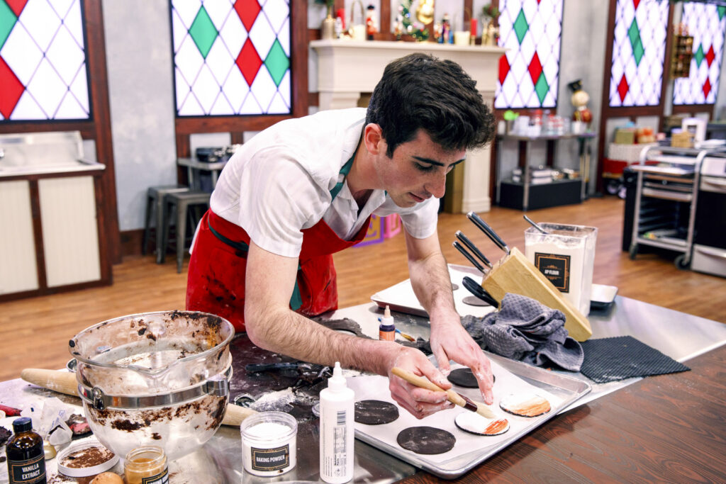 Contestant John Gerson works on his Christmas Cookies, as seen on Christmas Cookie Challenge, Season 6.