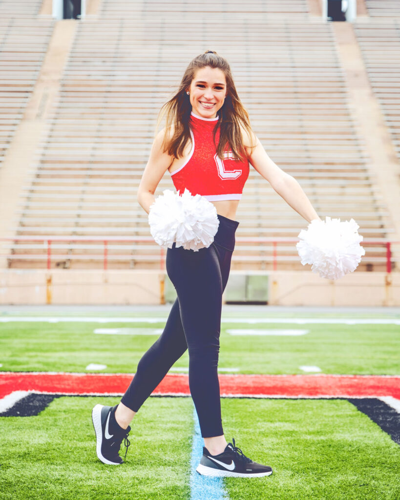Amanda Hernandez poses on the football field with a Cornell tank top on and pompoms in hand when she was a senior.