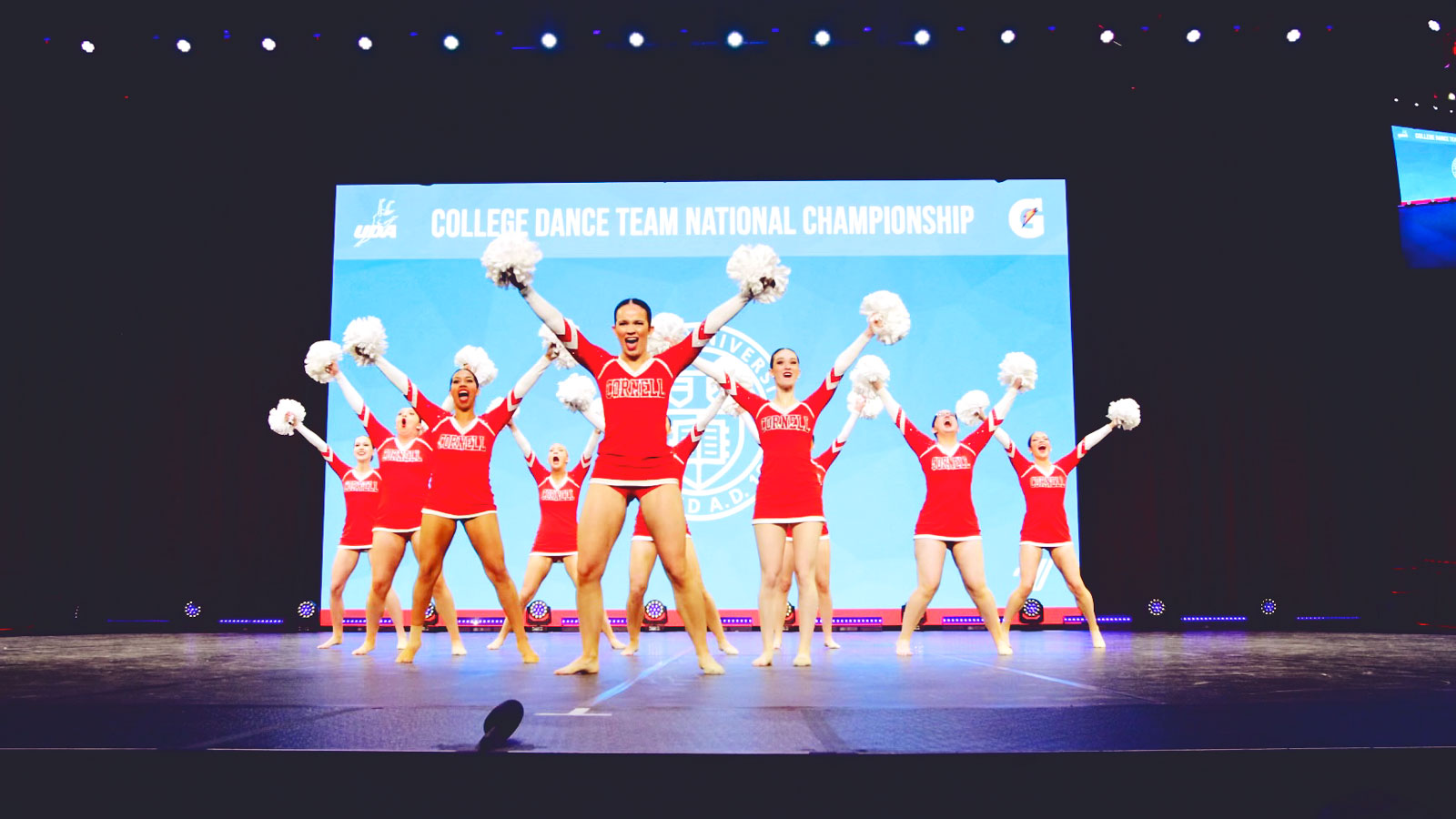 The Cornell University Dance Team members raise their pompoms and cheer on stage during their performance at the College Dance Team National Championship.