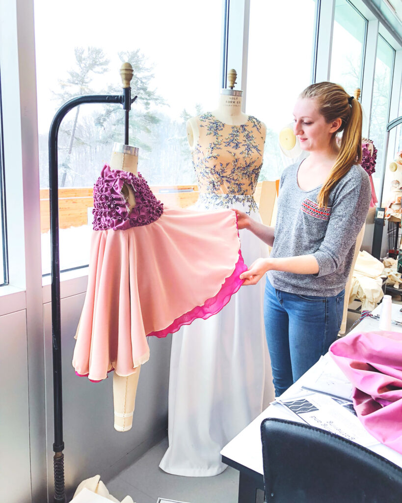 Julia DeNey inspects a dress on a hanger that she is in the process of designing.