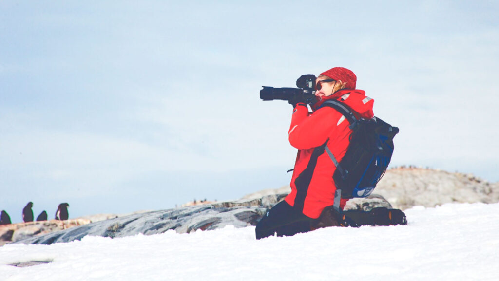 Dr. Rebecca Smith-Coggins taking photos of penguins in Antarctica