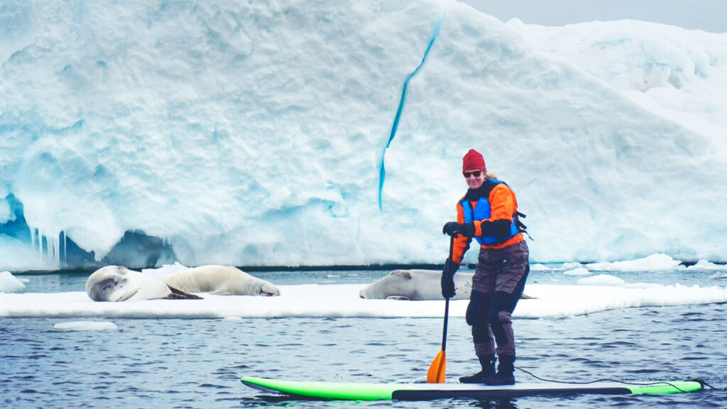 Dr. Rebecca Smith-Coggins paddleboarding past seals and glaciers in Antarctica