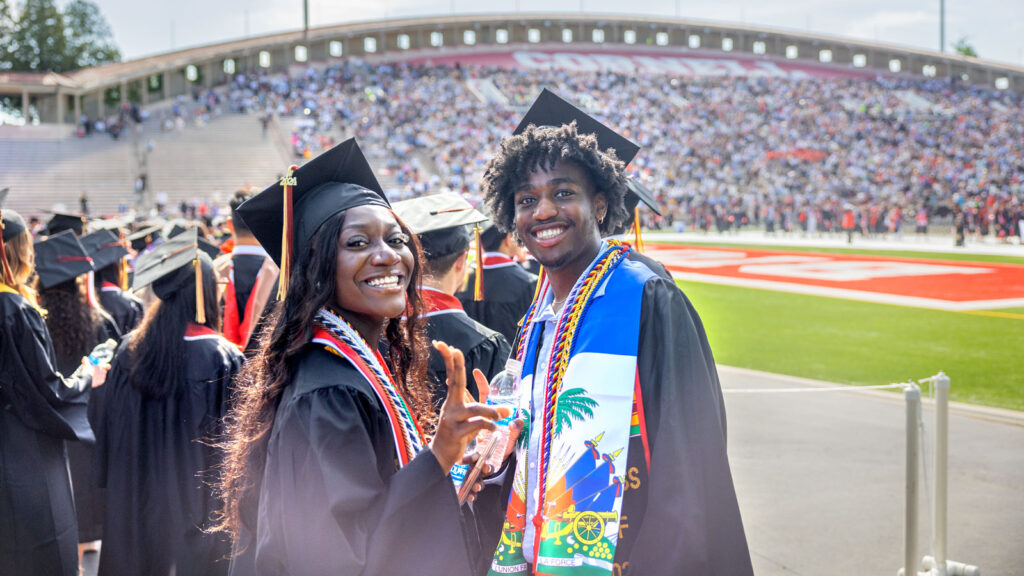 Two students celebrate at Schoellkopf Field during Commencement 2024