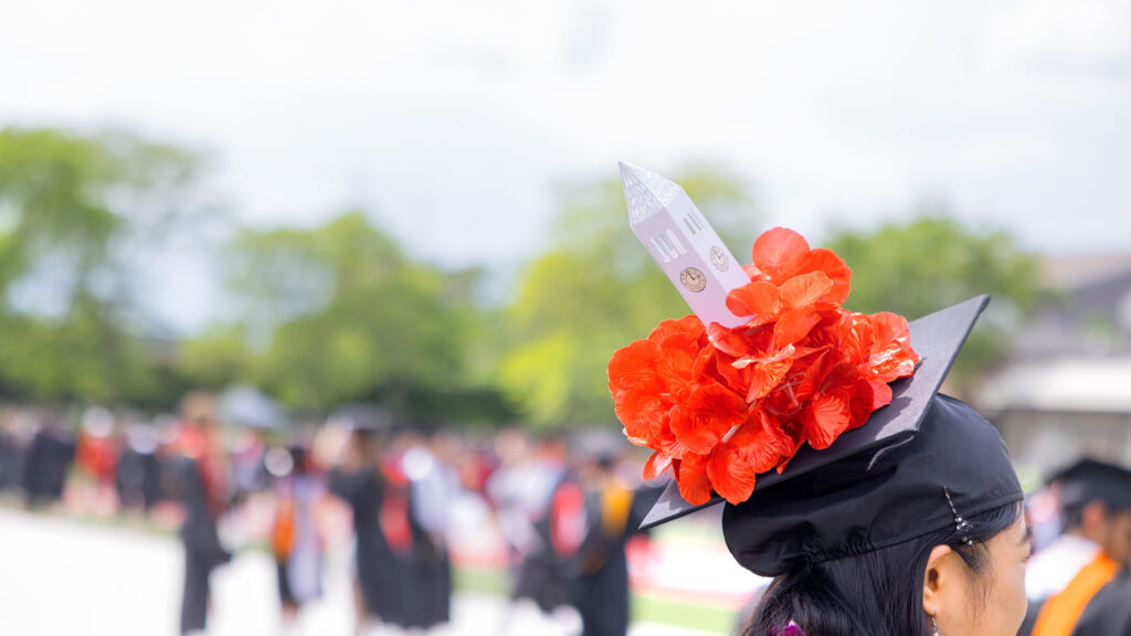 A decorated mortarboard with a mini McGraw Tower is seen atop a graduate's head during Commencement 2024 events