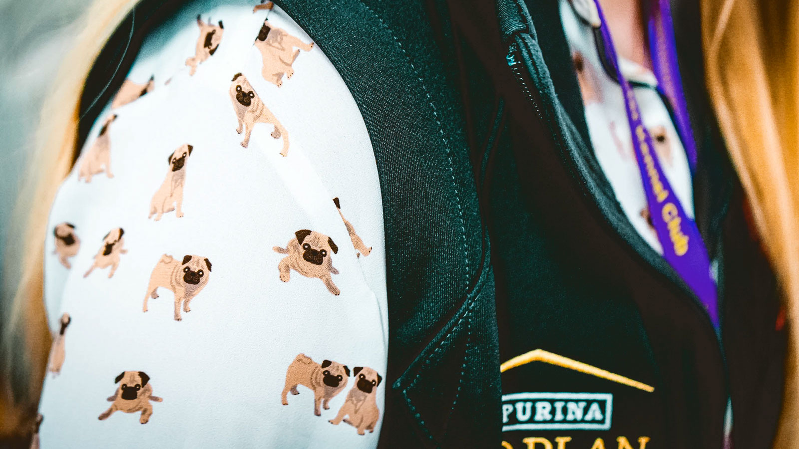 A woman's shoulder showing a shirt with a design of pug dogs