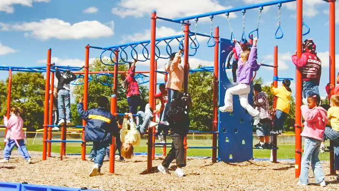 Children play on a set of climbing bars on a playground.