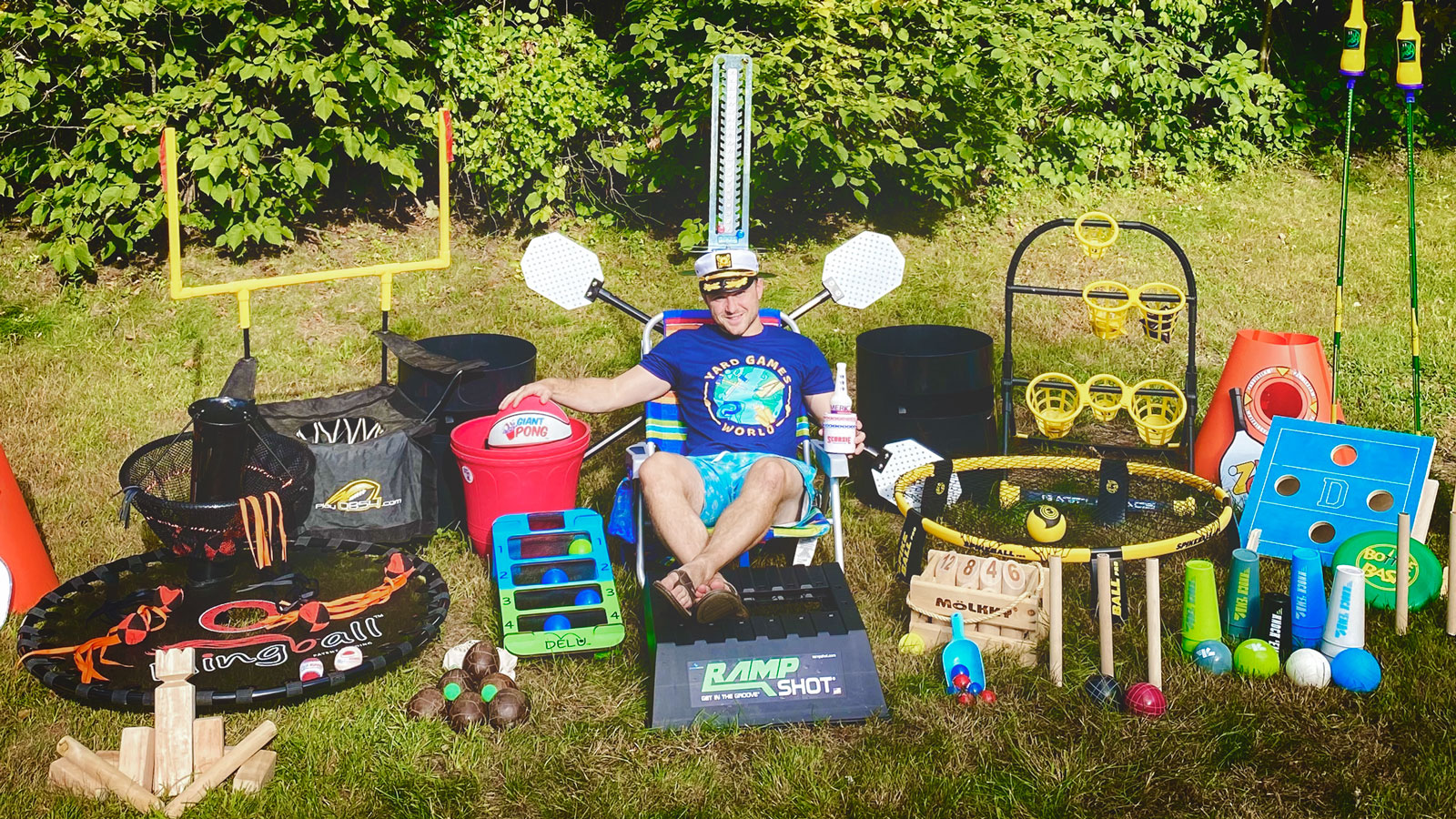 Matt Grear sits in a lawn chair on the grass surrounded by lawn games that he has acquired