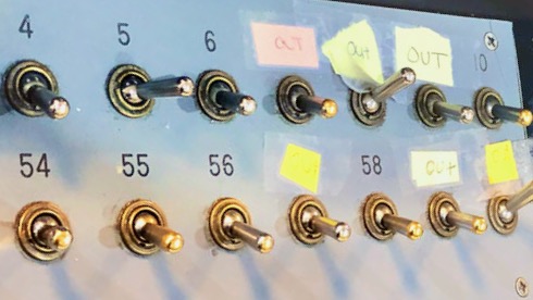 A behind-the-desk view shows some of the analog switches used to light up the sign’s numbers