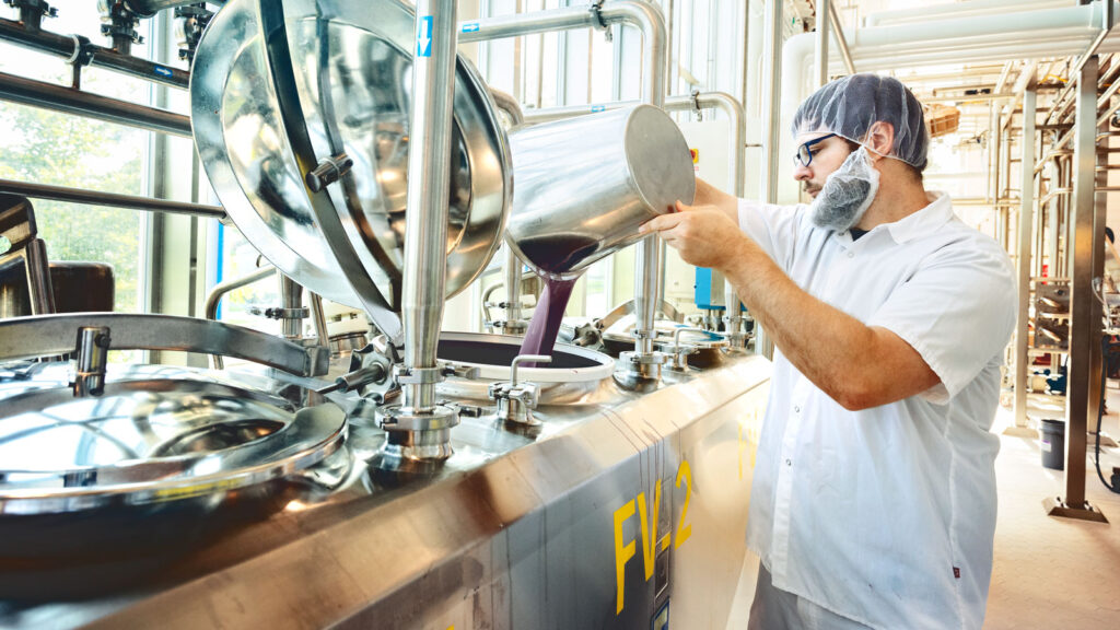 A man pours ice cream flavoring into a vat at the dairy plant
