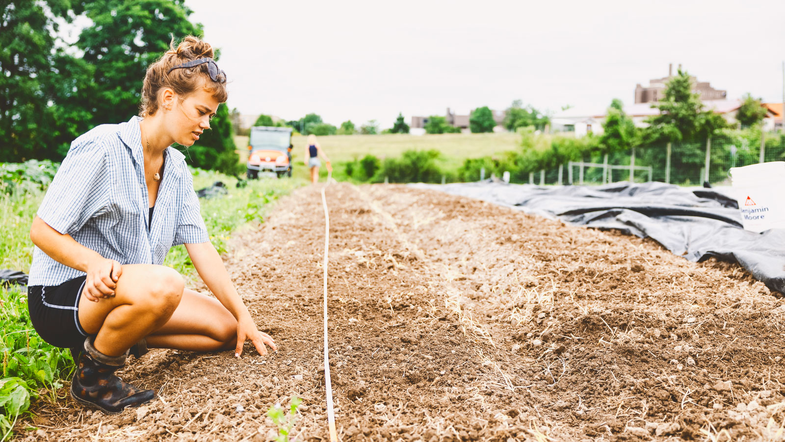 Student manager Izzie Beck inspects the soil in a garden bed