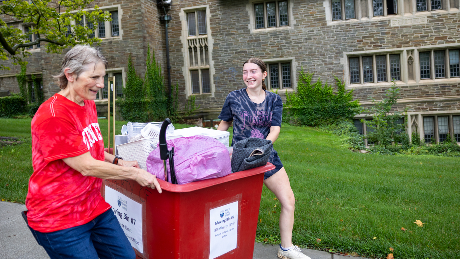 A student and family member move belongings in a bin in the rain during Move-In 2024 on West Campus