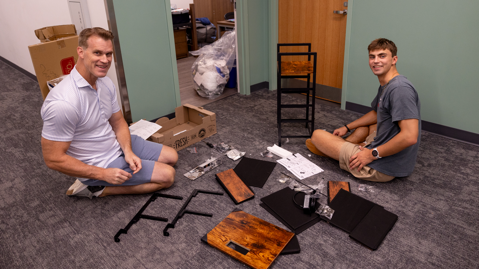 A student and parent begin work assembling a small furniture item in a North Campus residence hall during Move-In 2024