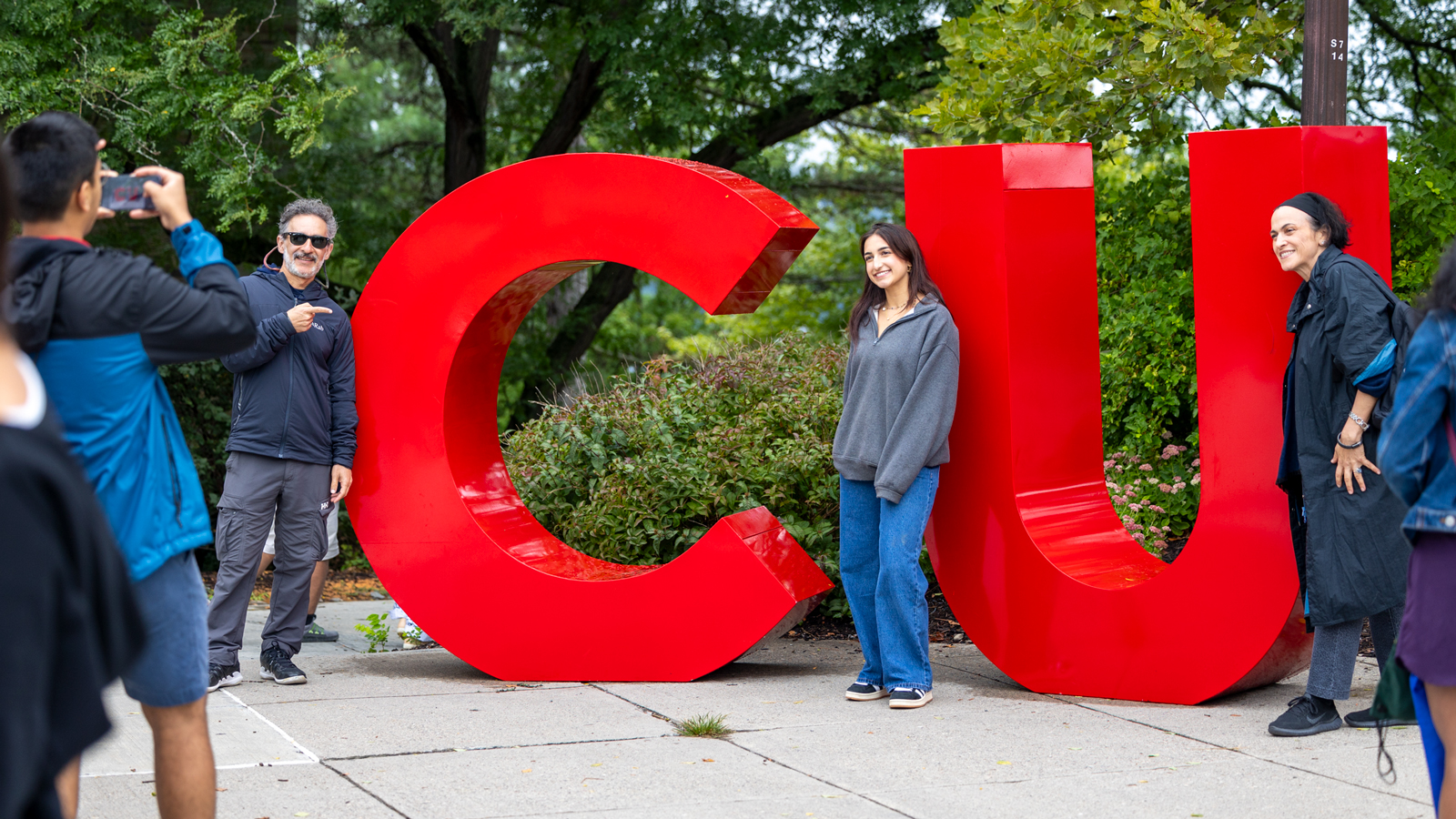 A student and family member pose by the large "CU" letters on Ho Plaza during the Big Red Welcome Fest