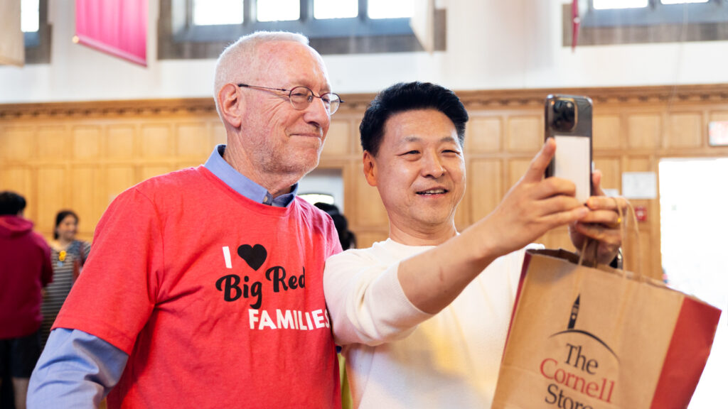 A parent poses for a selfie with Interim President Michael Kotlikoff during the Big Red Welcome Party for new Cornell families at Willard Straight Hall during Move-In 2024