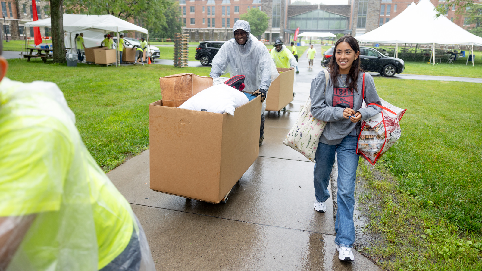 Students and parents move rolling bins of belongings on North Campus in the rain during Move-In 2024