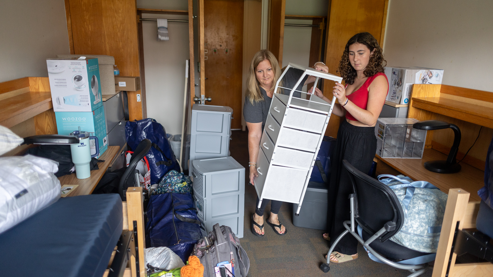 A student and parent move furniture and belongings into a residence hall room on North Campus during Move-In 2024