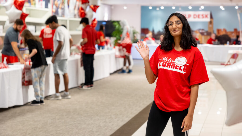 A volunteer welcomes new students at the check-in center at the Shops at Ithaca Mall during Move-In 2024