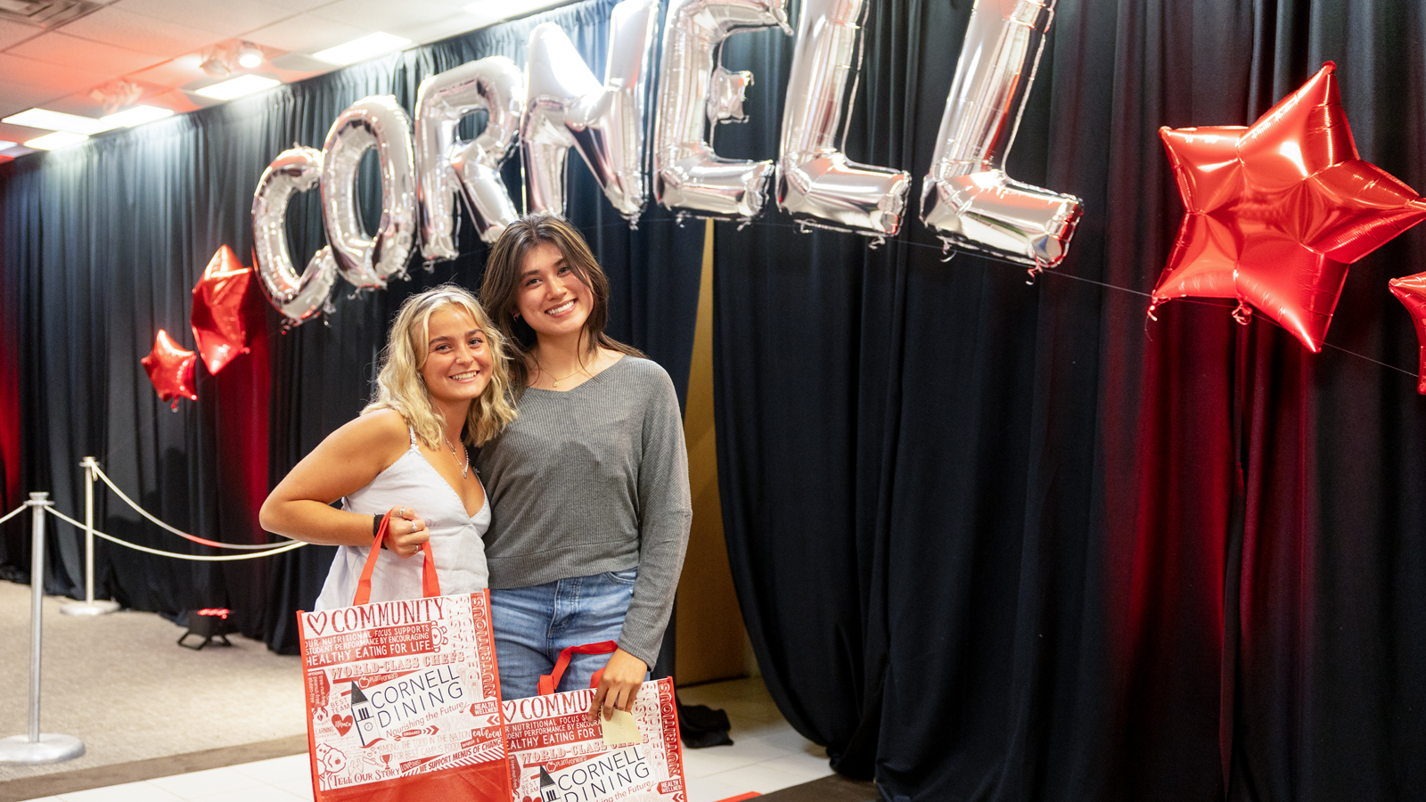 Students pose at the welcome and check-in center at the Shops at Ithaca Mall during Move-In 2024