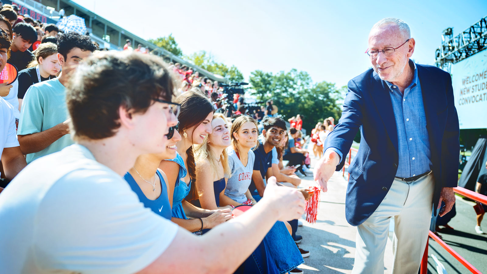 Mike Kotlikoff reaches out to shake a student's hand at Convocation.