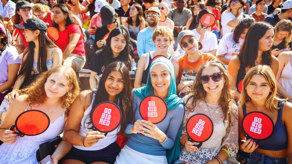 New students holding fans that say "Go Big Red" at Convocation.