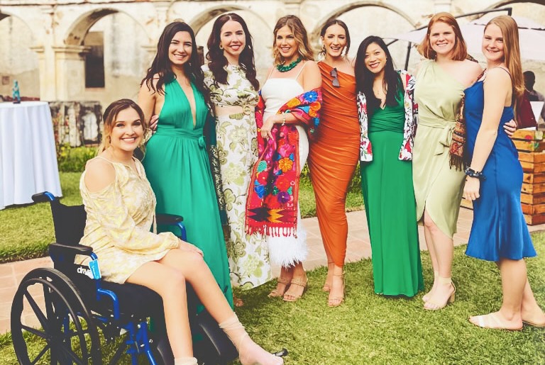 Nina Bachich in a wheelchair with a group of women wearing dresses