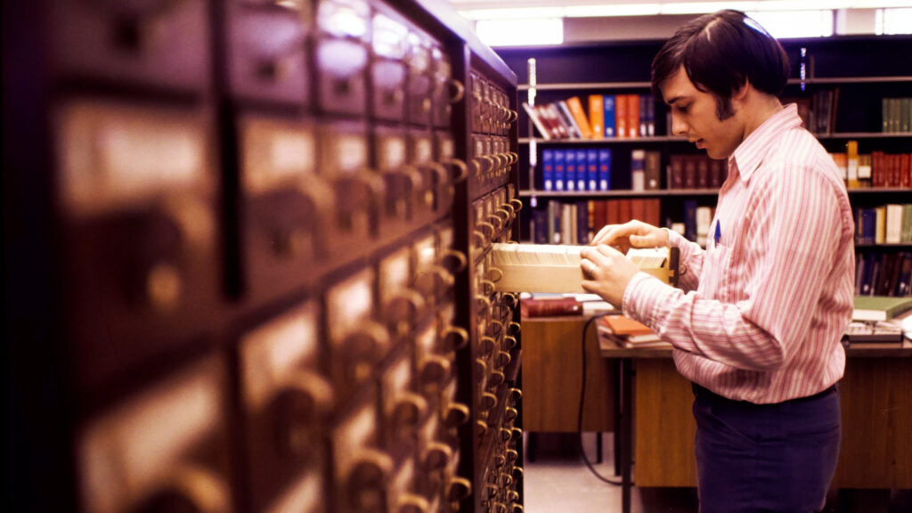 a library patron browses a card catalog at a University library, 1973