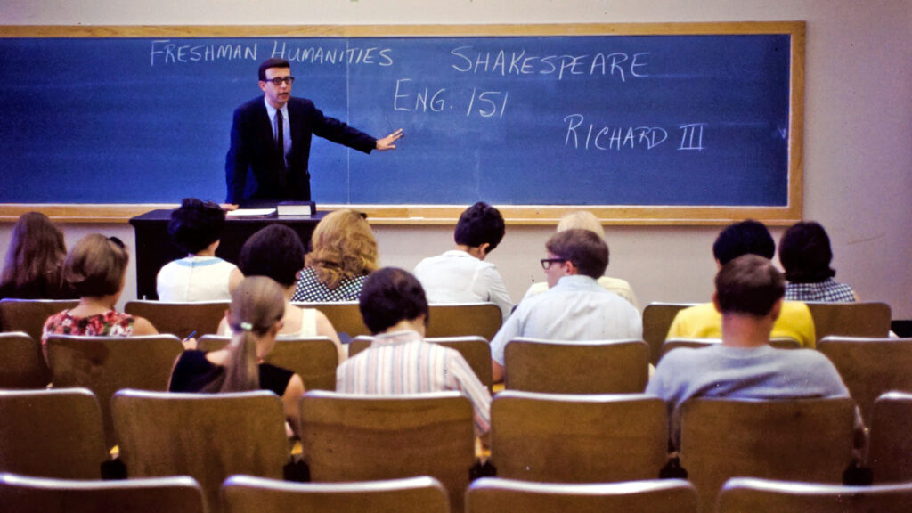 a freshman humanities class with writing visible on the blackboard, 1967