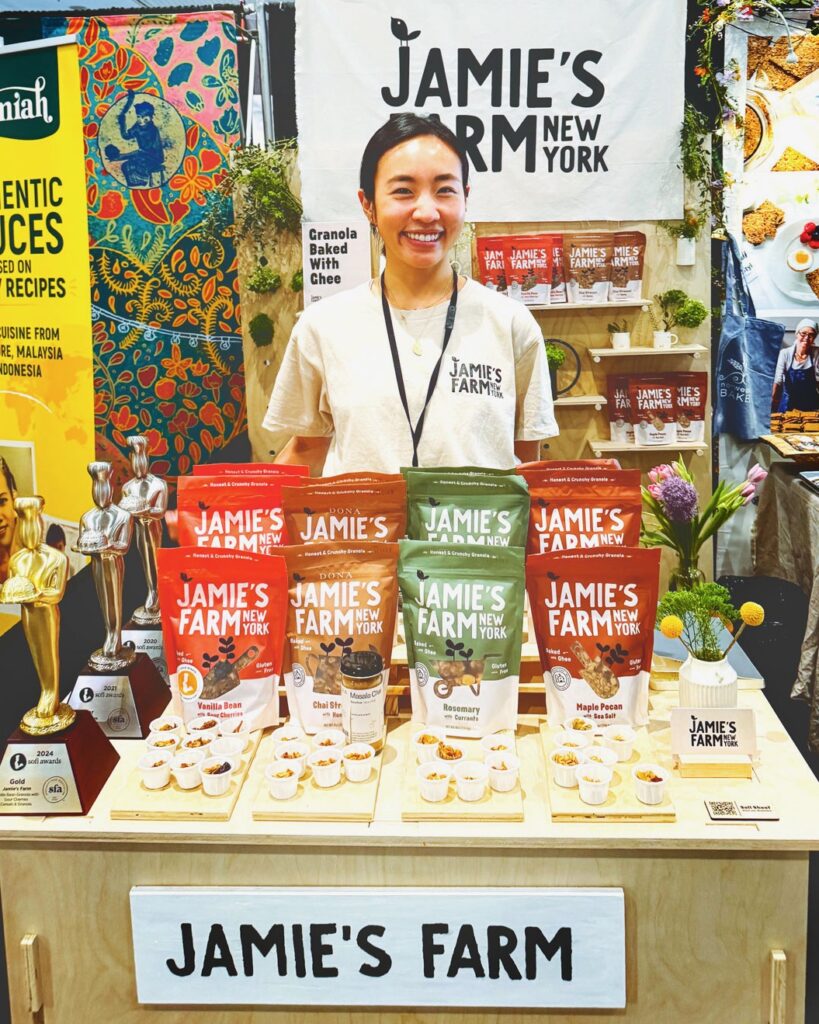 Jamie Kim smiles with a variety of her granola flavors