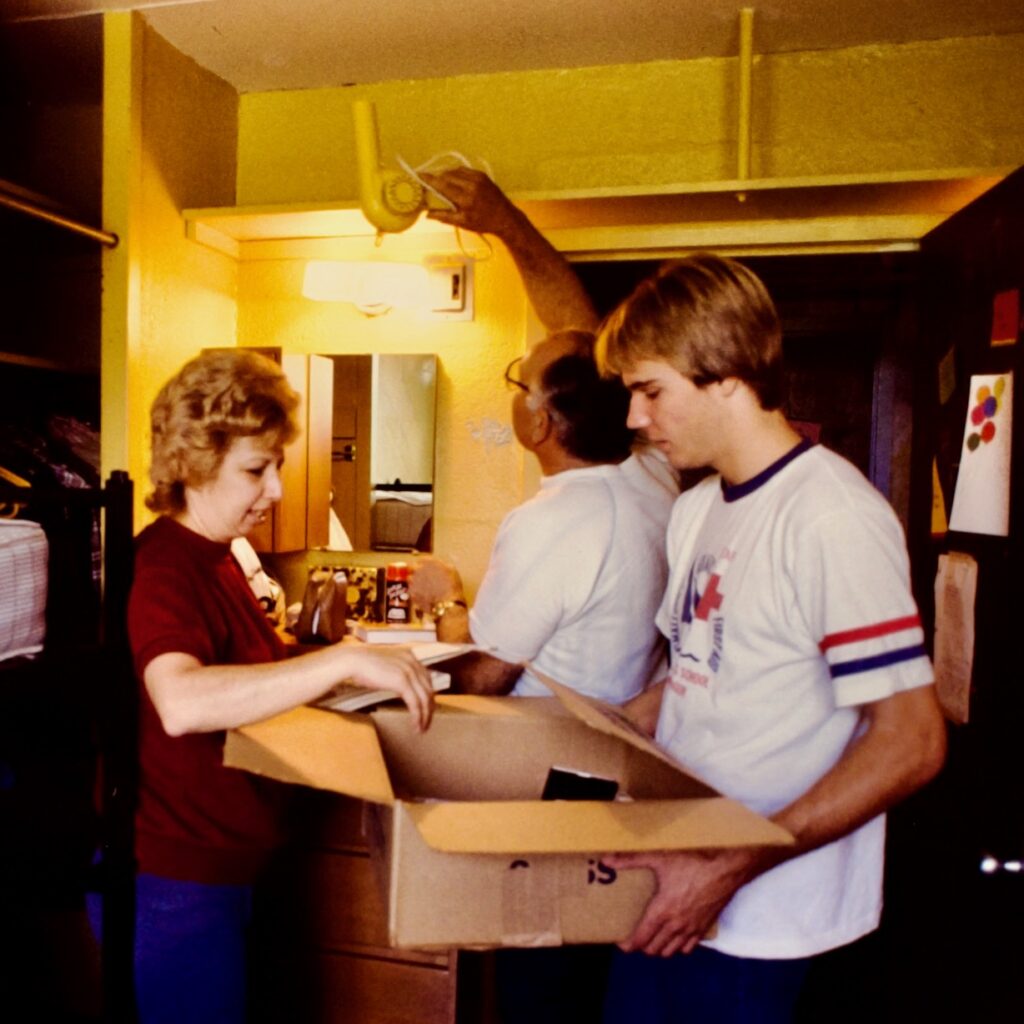 a student moves into a dorm room on campus with help from parents, 1982