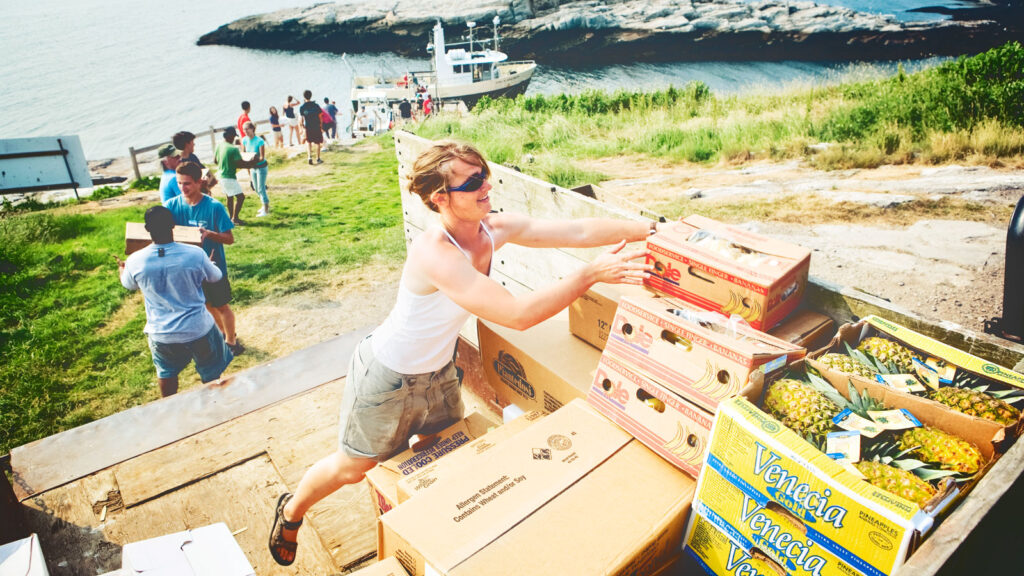 Student and faculty unload food from the boat together by forming a chain.