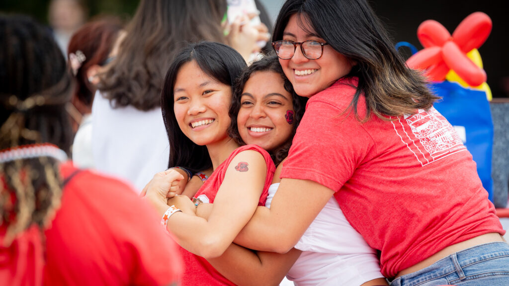 three attendees hug during the Big Red Fan Festival at Homecoming 2024