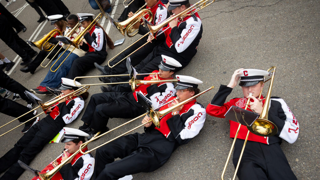 the trombones section of the Big Red Marching Band plays while lying on the ground during the Big Red Fan Festival at Homecoming 2024