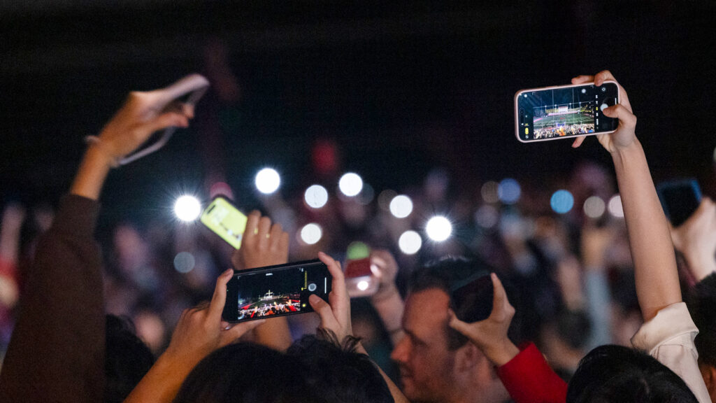 people in the crowd hold their phones aloft during the fireworks display at Schoellkopf Field for Homecoming 2024